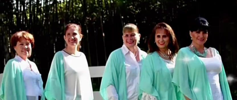 Las cinco socias fundadoras de Esencia del Alma, vestidas de blanco y color tiffany, en un jardín.